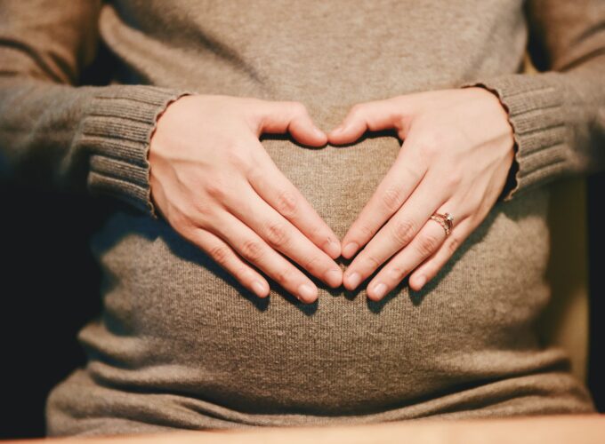 femme enceinte posant ses mains à plat en forme de cœur sur son ventre – le massage pendant le premier trimestre de grossesse