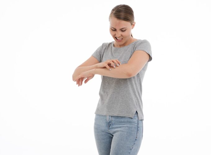 Une jeune femme se gratte le bras, qui démange en raison d’une maladie de peau